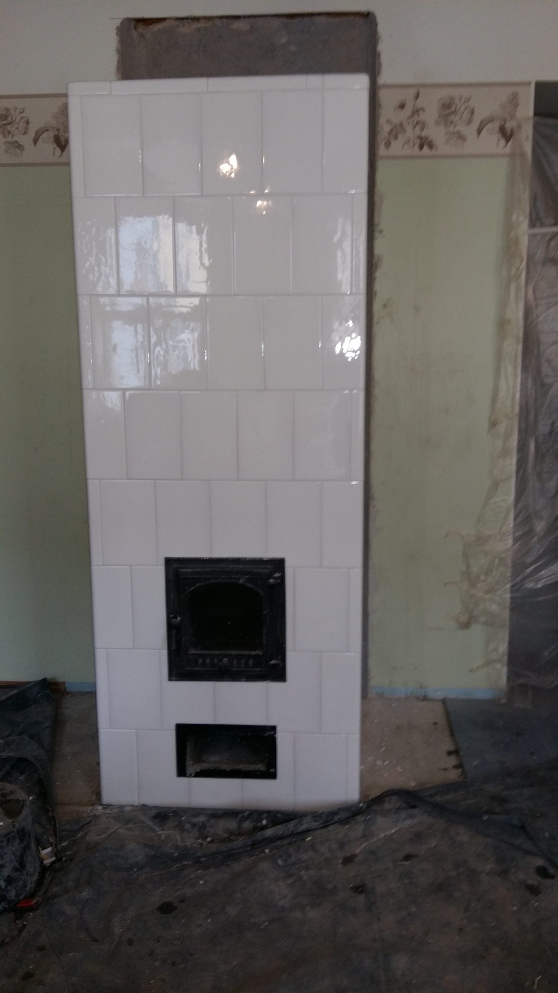 White tiled heater with a cast iron door, room under renovation