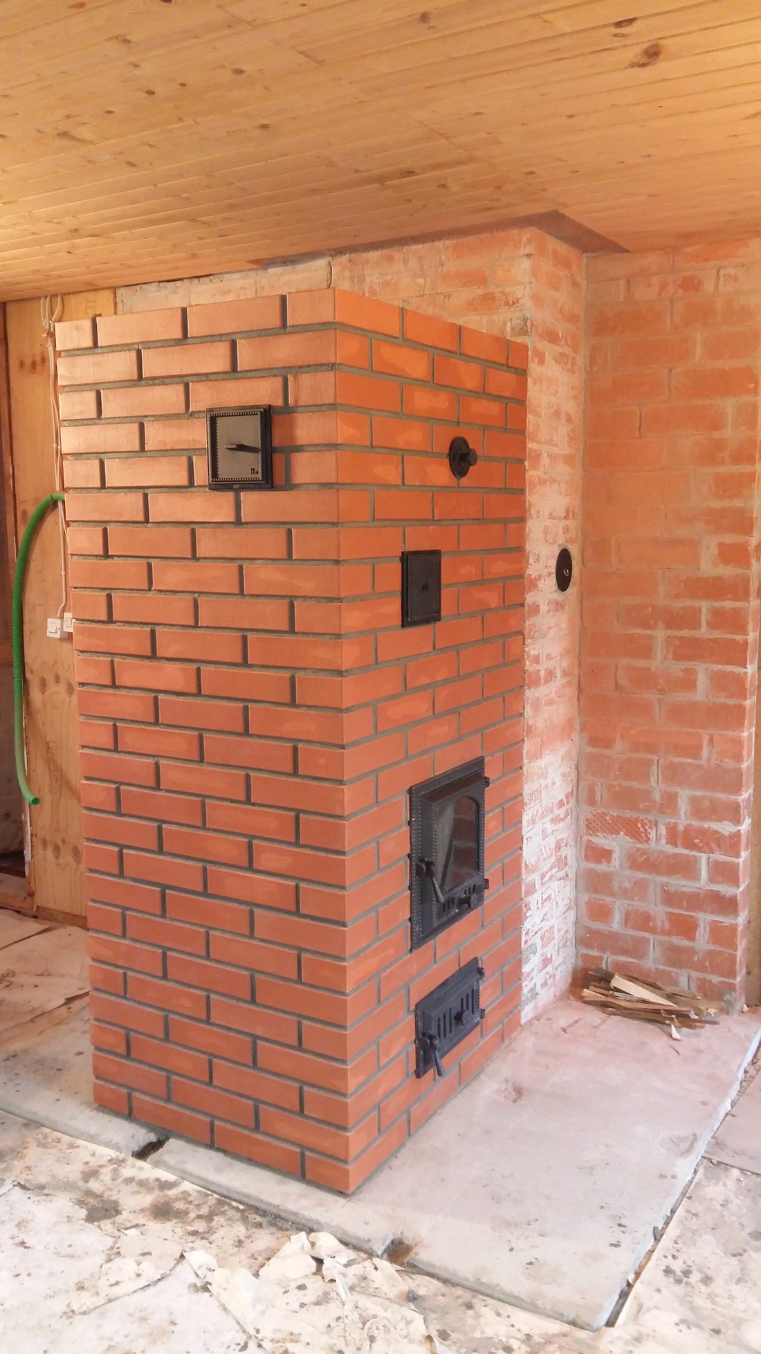 Brick fireplace heater with a glass-fronted firebox, ash door and thermometer