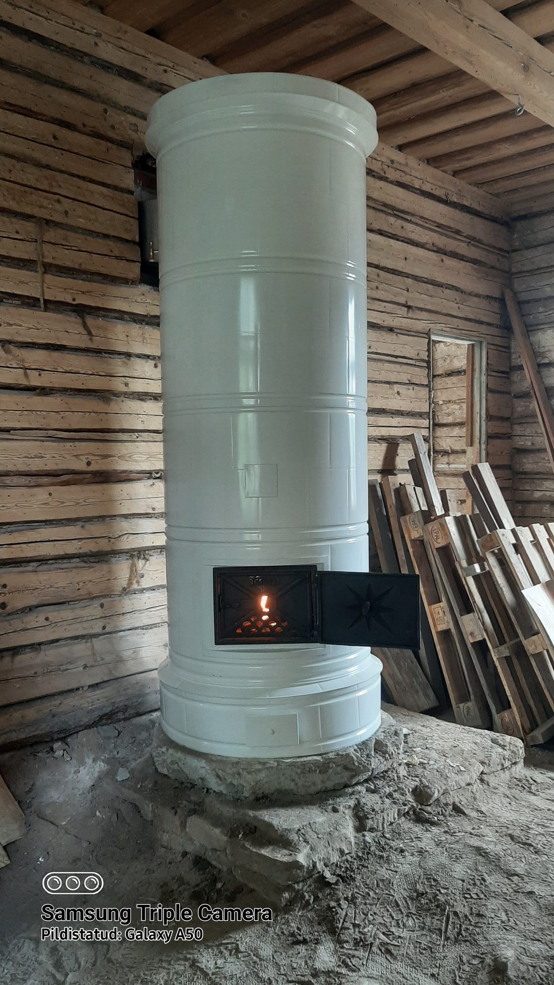 Round white tiled heater with a fire burning in the firebox